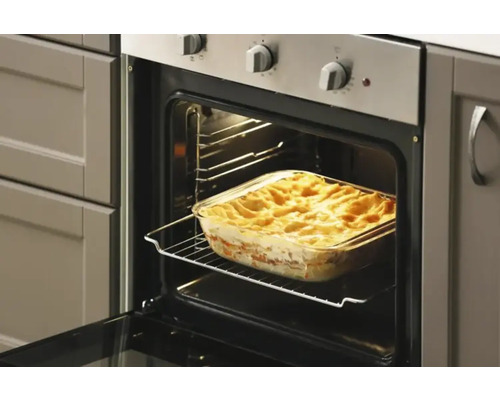 Ugn med lasagne i en ugnsform på ett galler