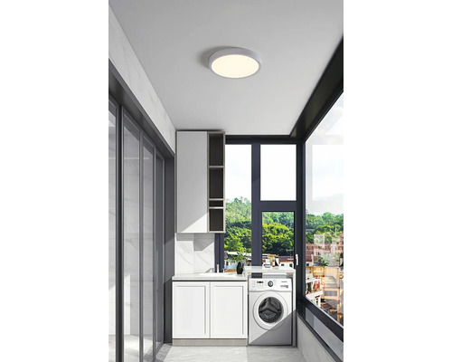 Ljust tvättrum med tvättmaskin, handfat, skåp och rund taklampa