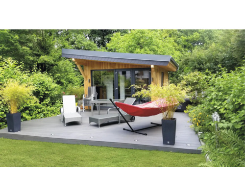 Trädgårdshus med altan, trädgårdsmöbler och hängmatta i grönområde