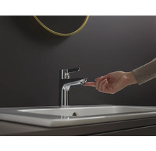 En hand manövrerar en metallkran på ett handfat.