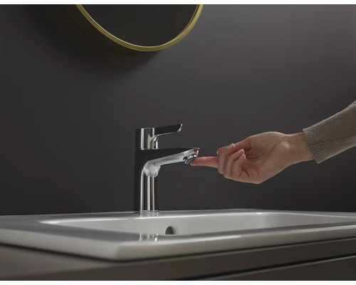 En hand manövrerar en metallkran på ett handfat.