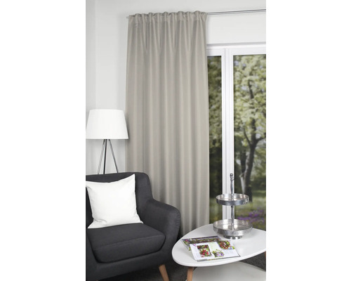 Dekorativ gardin bredvid fåtölj och bord i ett vardagsrum