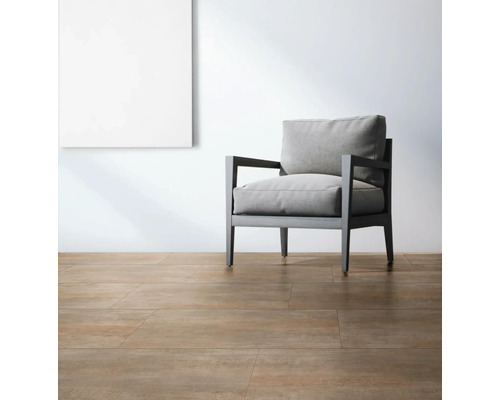 Ljust rum med golvplattor, fåtölj och en tavla på väggen