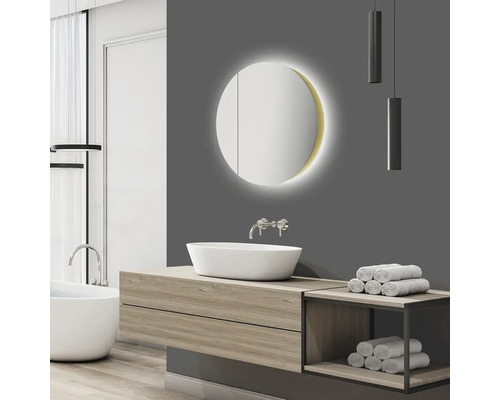 Badrum med tvättställ, rund spegel med belysning och handdukar