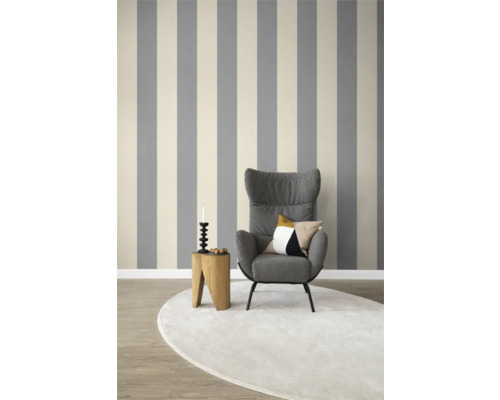 Vardagsrum med randig tapet, fåtölj, matta och sidobord