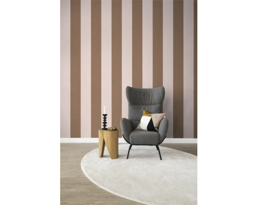 Vardagsrum med randig tapet, fåtölj, sidobord och matta