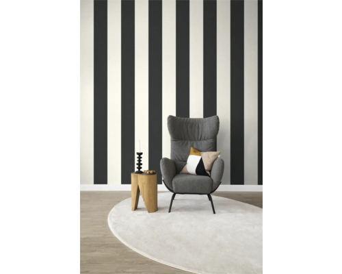 Vardagsrum med randig tapet, fåtölj och rund matta