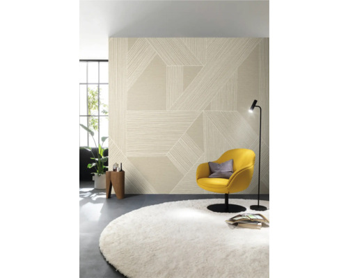 Vardagsrum med mönstrad tapet, fåtölj, matta och golvlampa.