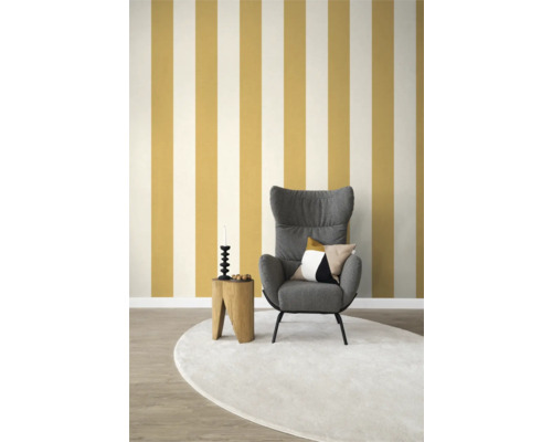 Vardagsrum med fåtölj, sidobord, dekorationer och randig tapet