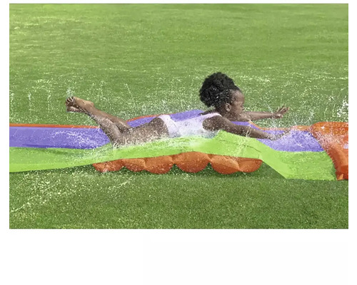 Barn glider på en vattenrutschkana i trädgården