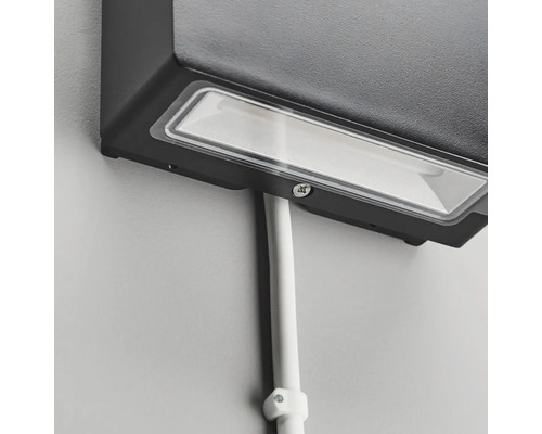 Närbild av en svart utomhuslampa med kabel på en vägg.