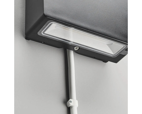 Närbild av en svart utomhuslampa med kabelkanal på en vägg