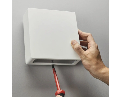 Installation av en kvadratisk vägglampa med en skruvmejsel.