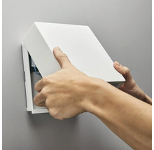 Person monterar en kopplingsdosa på väggen