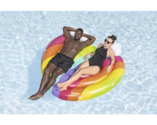 Två personer kopplar av på en färgstark, uppblåsbar poolö i vattnet.