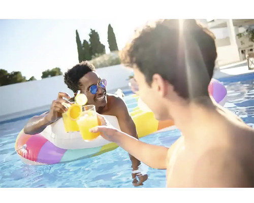 Två män skålar med drinkar i en pool med en uppblåsbar badring.