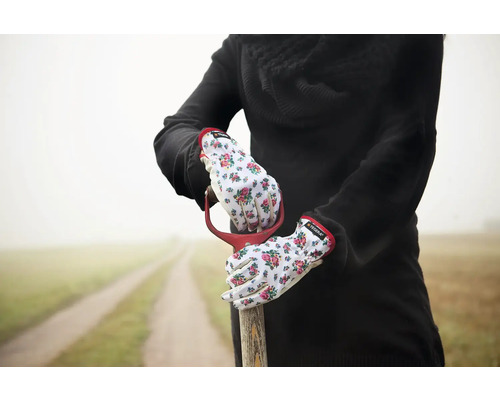 En person med trädgårdshandskar håller en spade