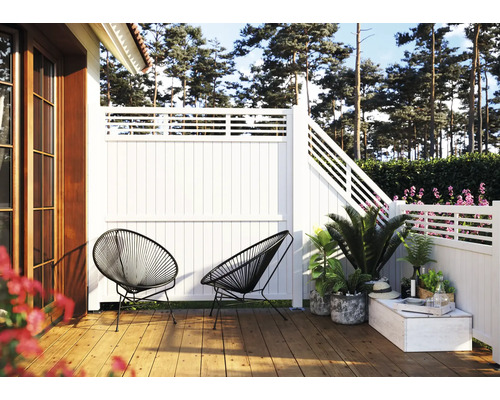 Terrass med trägolv, vitt staket och två svarta stolar