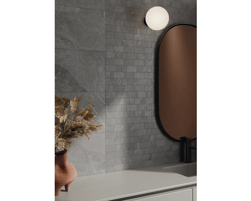 Badrum med grå kakel, spegel och lampa