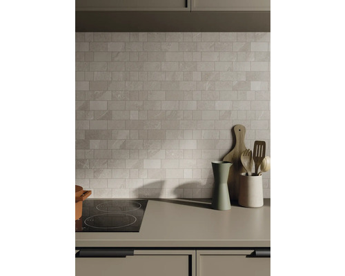 Köksscen med kakelvägg, spishäll och köksredskap på bänkskivan.