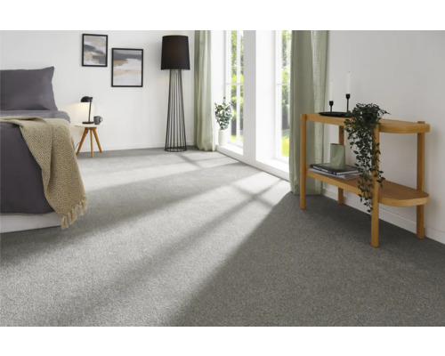 Ljust sovrum med heltäckningsmatta, säng, golvlampa och sidobord