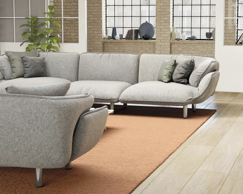 Ljust vardagsrum med grå hörnsoffa, prydnadskuddar och matta