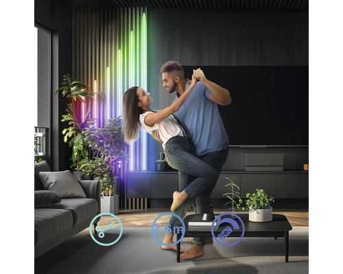 Ett par dansar i ett vardagsrum inrett med LED-lampor och krukväxter.