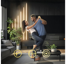 Par dansar i ett vardagsrum med en modern golvlampa på ett bord.