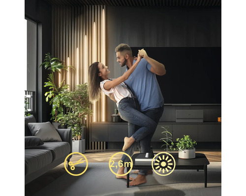 Par dansar i ett vardagsrum med en modern golvlampa på ett bord.