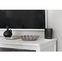 Dekorativa föremål och elektronisk apparat på en vit skänk framför en TV.