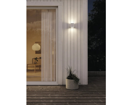 Belyst husvägg med två utomhuslampor och en planteringslåda