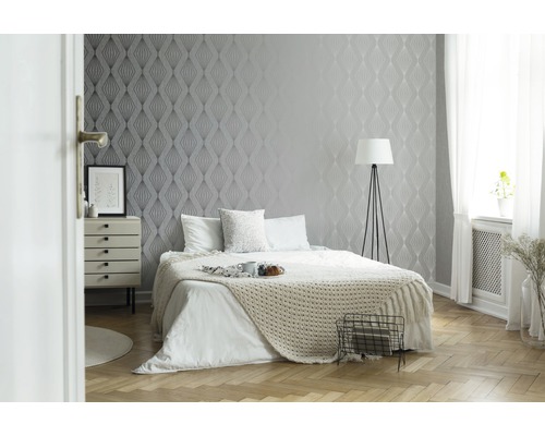 Sovrum med mönstrad tapet, säng och nattduksbord