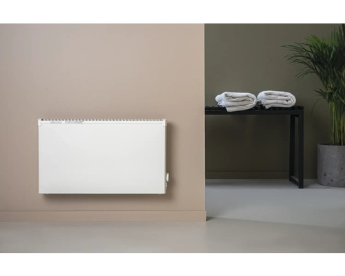 Platt värmepanel på väggen med handdukar och krukväxt i bakgrunden