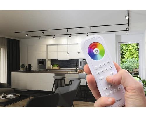 Modernt vardagsrum med skensystembelysning och en fjärrkontroll för att styra belysningen.