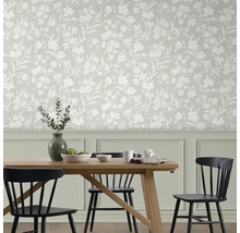 Matsal med matbord och stolar framför vägg med blommig tapet