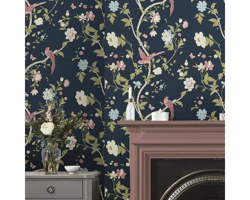 Rumsbild med blommig tapet, öppen spis och byrå