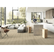 Ljust, öppet vardagsrum med trägolv, grå soffa och köksö