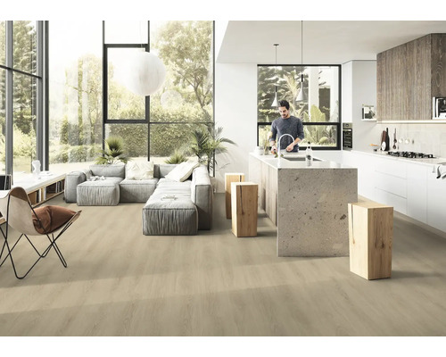 Ljust, öppet vardagsrum med trägolv, grå soffa och köksö