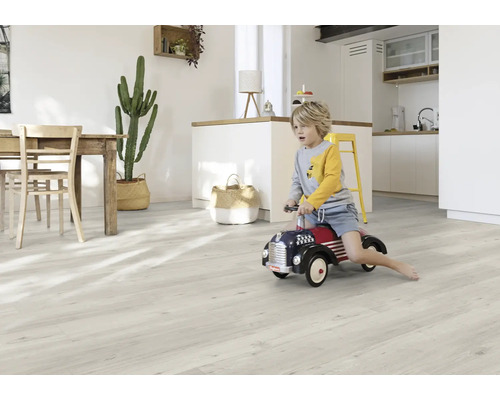 Ljust vardagsrum med träbord, kaktus, pojke på leksaksbil och ljust trägolv.