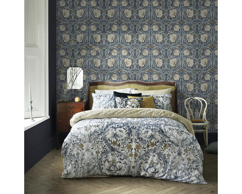 Sovrum med blommönstrad tapet, säng med blommiga sängkläder, nattduksbord och stol.