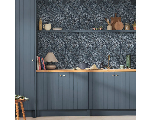 Köksscen med blå tapet med bladmönster, blå skåp och trähyllor