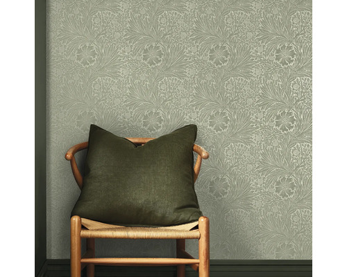 Stol med kudde framför en vägg med ett blommigt tapetmönster