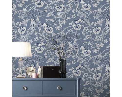 Dekorativt rum med blommig fiberdukstapet på väggen, byrå, lampa och dekorationer.