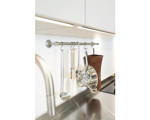 Köksredskap hänger på en rostfri stång i köket.