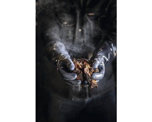 En person håller ryckigt, rökande kött med handskar.