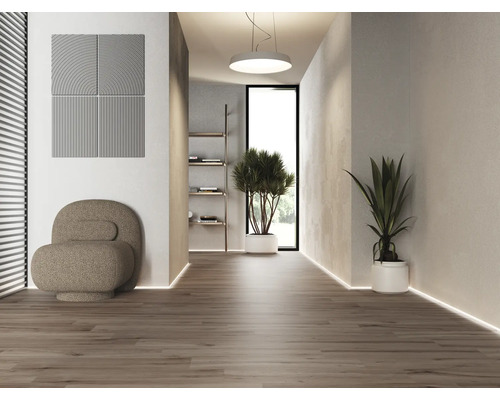 Ljus inredning med akustikpaneler, fåtölj och krukväxter på trägolv.