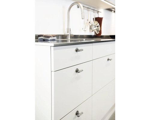 Köksdel med diskho, blandare och vita skåpfronter