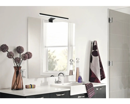 Modernt badrum med handfat, spegel, lampa och dekorationer.