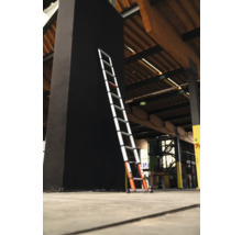 Teleskopstege lutad mot en svart pelare i en byggnad