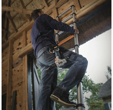 Hantverkare på en teleskopstege med en batteridriven skruvdragare i bältet på jobbet.